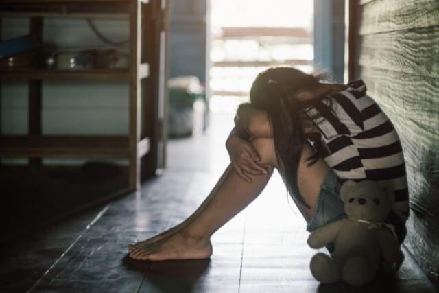 Niña llorando en su cuarto con un oso de peluche por el matrimonio infantil