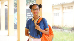 Estudiante dominicana sonriente en su escuela, destacando la importancia de la educación de calidad para romper los ciclos de pobreza y desigualdad en República Dominicana.