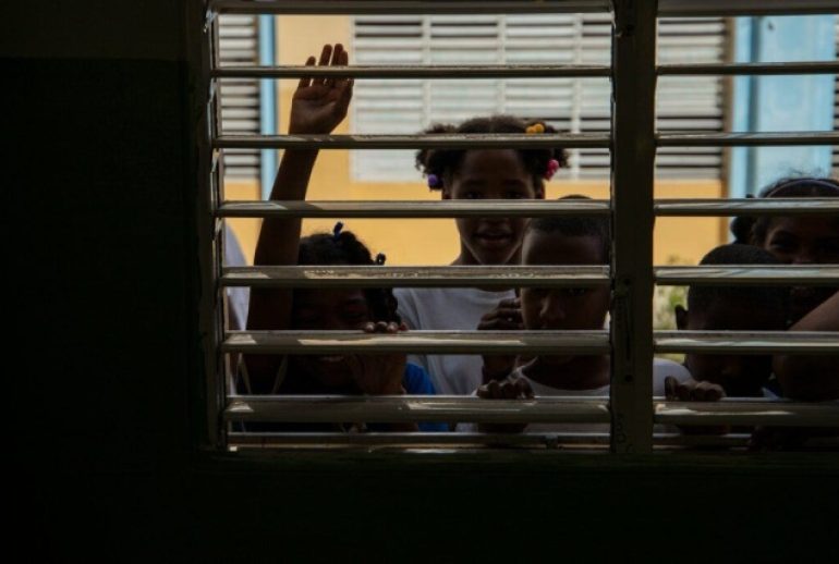 Niños y niñas dominicanos viendo a través de una ventana
