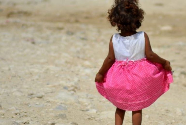 Niña con falda rosada caminando sola en la tierra